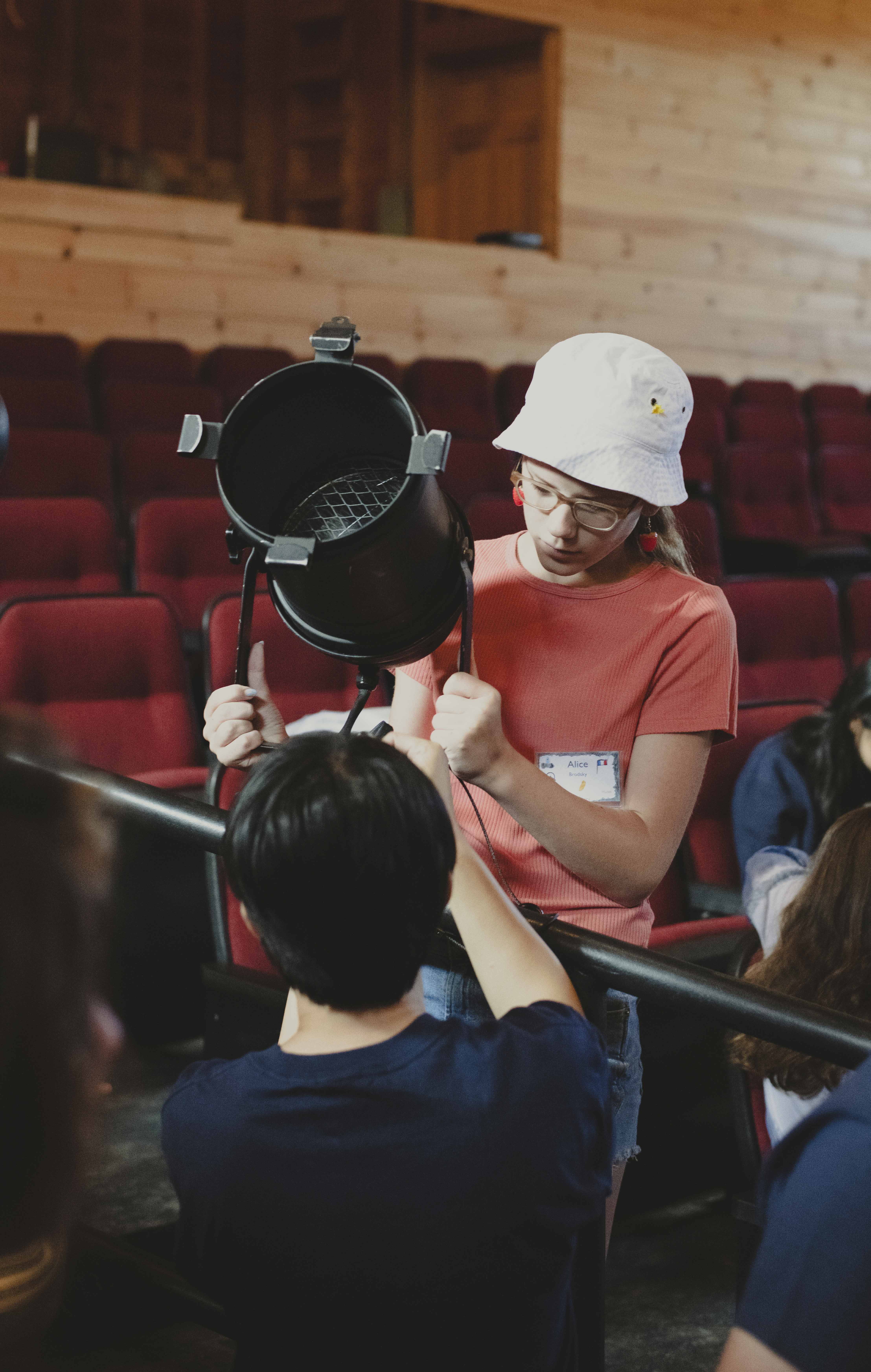 A camper learns how to harness a light fixture in the theater